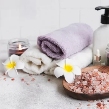 spa-set-essential-oil-massage-salt-candle-frangipani-flowers-gray-concrete-background_87742-21093